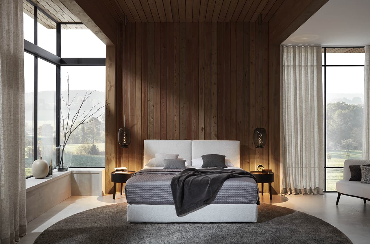 Helles Schlafzimmer mit warmem Holz und einem modernen Polsterbett.
